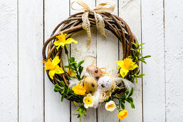 Easter background with spring easter eggs and flowers, wreath on door