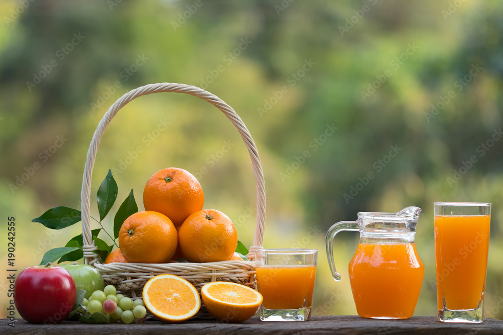 glass of fresh orange juice with fresh fruits on wooden table over green bokeh background glass of fresh orange juice with fresh fruits on wooden table over green bokeh background