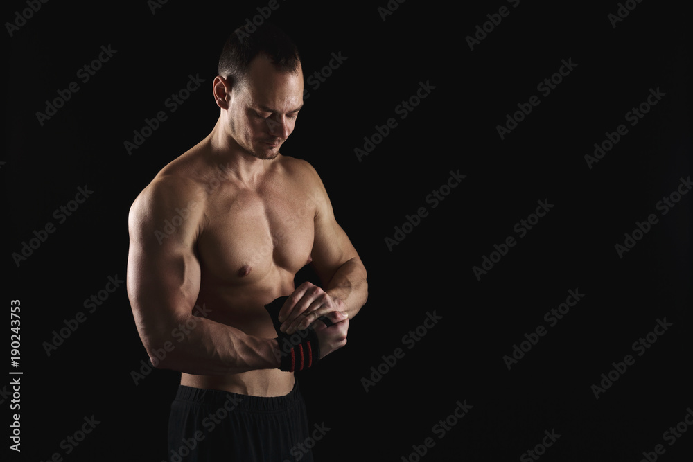 Athletic boxer wrapping hands with boxing bandage Athletic boxer wrapping hands with boxing bandage