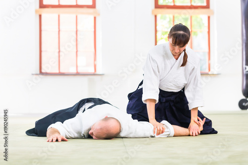 Man and woman fighting at Aikido training in martial arts school 