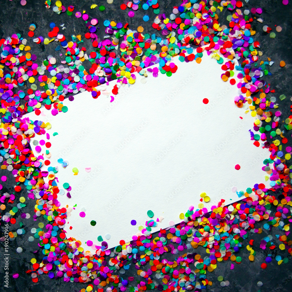 White sheet of paper in frame made of colorful confetti on black textured background.