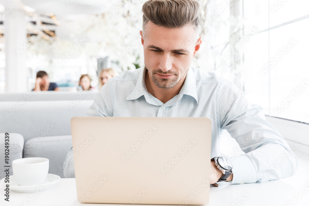 concentrated handsome businessman working with laptop at cafe concentrated handsome businessman working with laptop at cafe