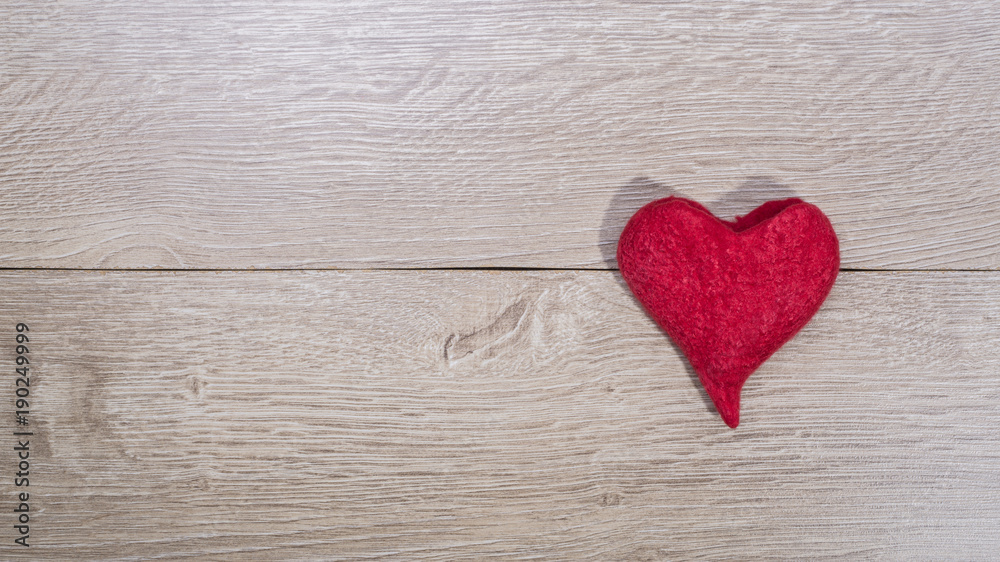 valentine made of felted wool in the shape of a heart on a wooden surface valentine made of felted wool in the shape of a heart on a wooden surface