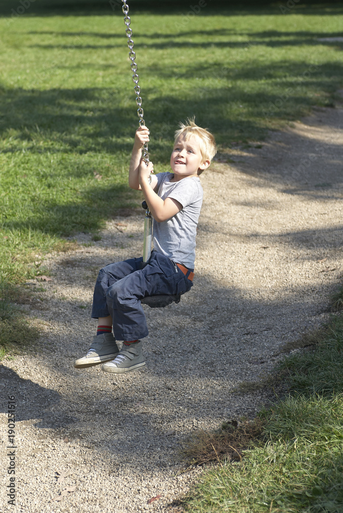 Child boy rides on Flying Fox play equipment in a children's playground, summertime
