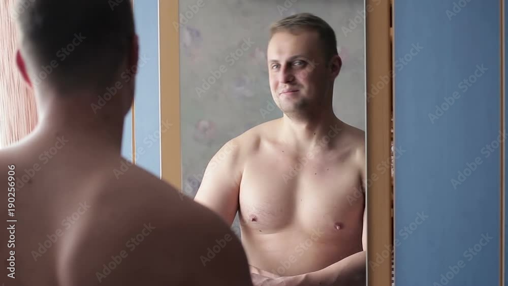 Funny narcissist guy straining his muscles in front of the mirror Funny narcissist guy straining his muscles in front of the mirror