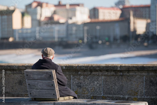 Senior man using a hearing device sitting in front of the sea