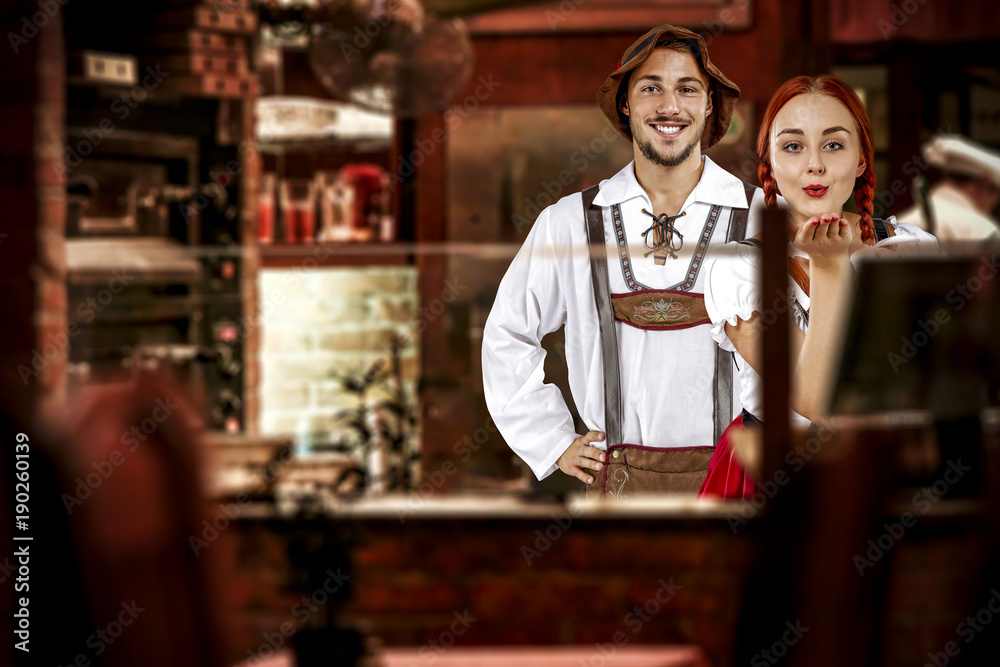 young two people in bavarian clothes and small business of bar . 