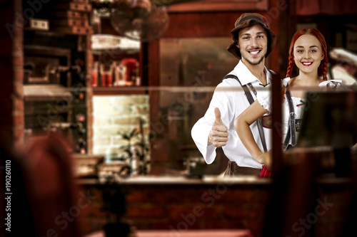 young two people in bavarian clothes and small business of bar . 