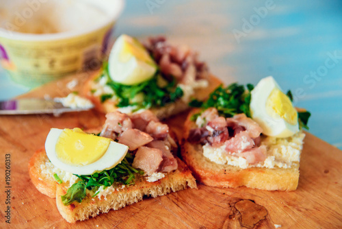 bruschetta, appetizer, canapes: fish tuna and spinach on toast of white bread, with egg on wooden Board