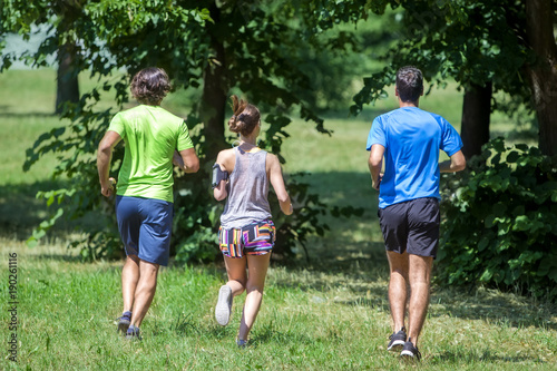 Woman and two young men running in the park