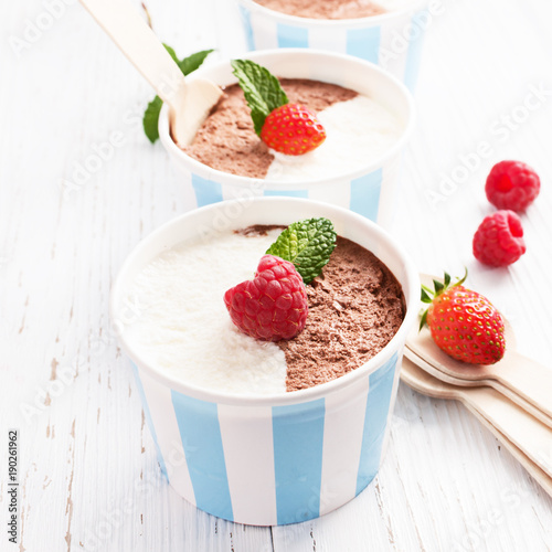 Chocolate vanilla ice cream with summer berries on white wooden board. Selective focus  copy space.