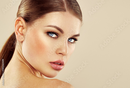 Beauty portrait of glamour model with perfect healthy skin and smoky eyes makeup over studio background with copy space. 