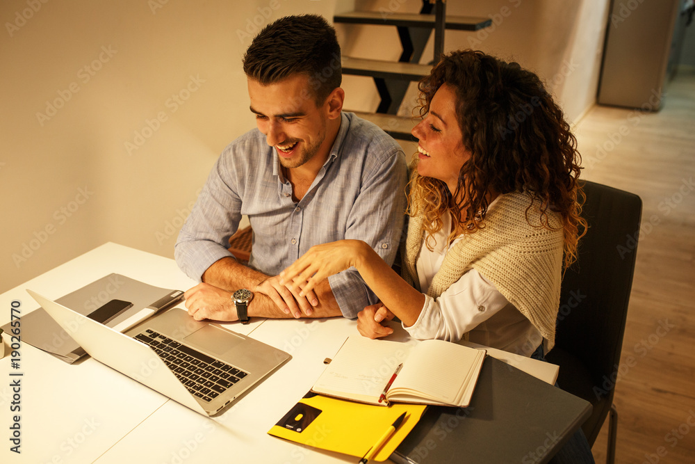 Married couple sitting at the table in they living room and using laptop.Calculate home budget.
