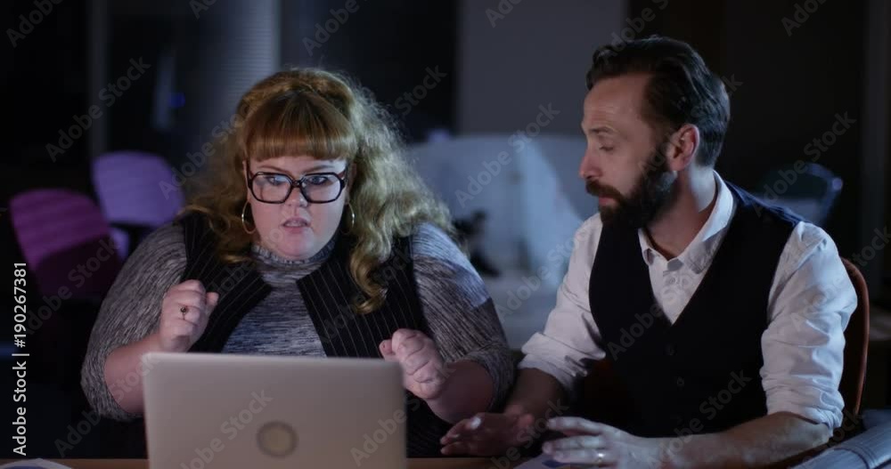 4K Happy small business partners working late, working on computer & seeing positive business results. Slow motion