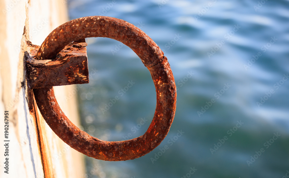 Rusty bollard waits at quay for a boat to be tied. Blur sea for background, closeup, details, banner Rusty bollard waits at quay for a boat to be tied. Blur sea for background, closeup, details, banner