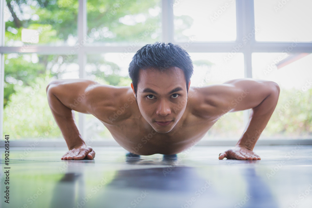 Asian muscular guy doing push-ups exercise on the floor Asian muscular guy doing push-ups exercise on the floor