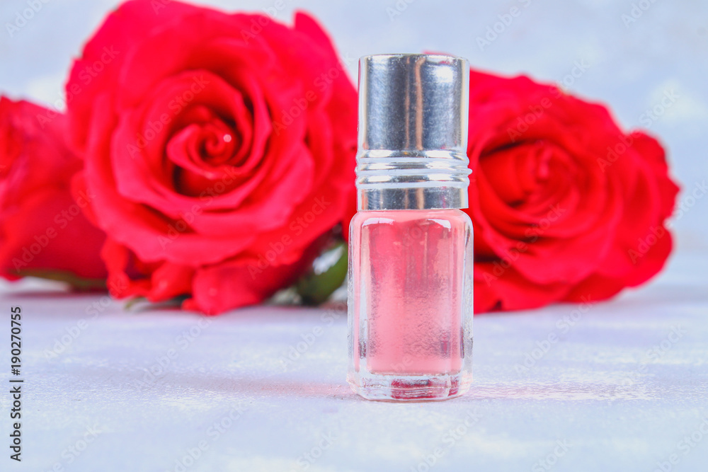 Pink water, oil from petals of pink roses on a gray table. Pink water, oil from petals of pink roses on a gray table.