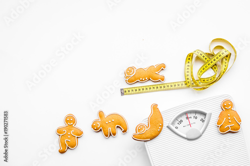 Ways for lose weight. Sport. Cookies in shape of yoga asans near scale and measuring tape on white background top view copy space