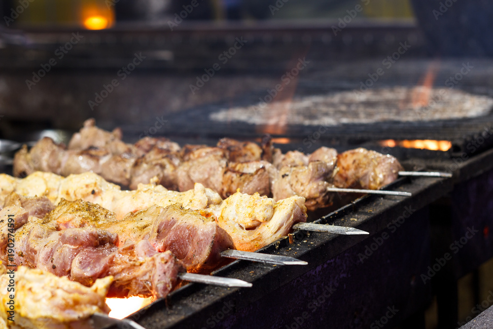The process of cooking shish kebab on a metal grill in the open air.Grilling shashlik on barbecue grill. Marinated meat.