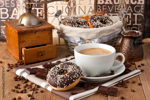 Cup of coffee with milk and chocolate donut on a wooden table