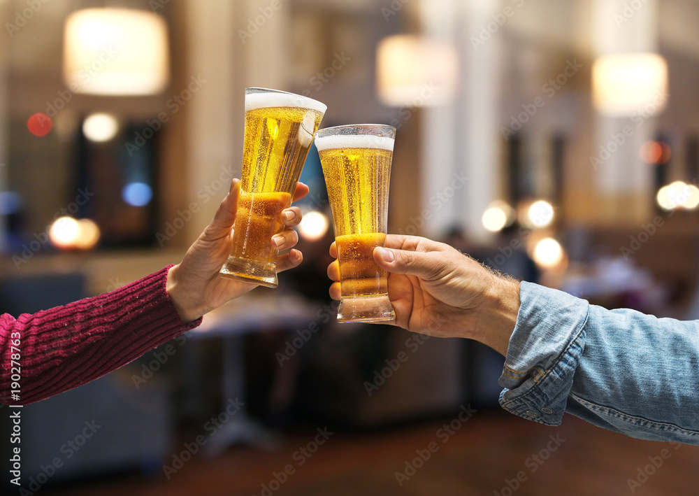 Beer glasses raised in a toast. Close-up hands with glasses. Beer glasses raised in a toast. Close-up hands with glasses.