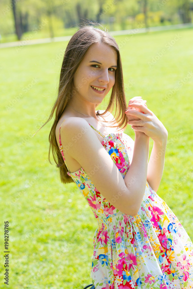 Portrait of young beautiful woman with long hair wearing flower dress in green spring park Portrait of young beautiful woman with long hair wearing flower dress in green spring park