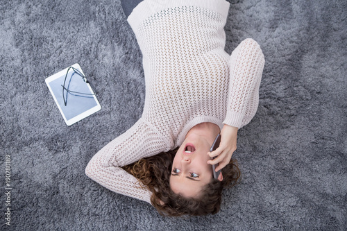 Картината върху платно Surprised Girl Lying on Carpet Speaking on Phone