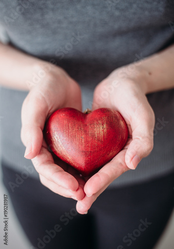 Fototapeta Naklejka Na Ścianę i Meble -  Female hands holding red wooden heart. concept for St. Valentine's Day