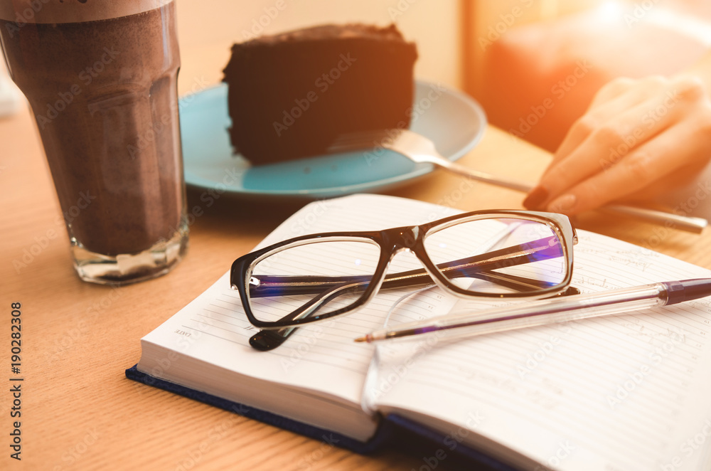 Notebook with glasses, cake and coffee. Working or planning concept Notebook with glasses, cake and coffee. Working or planning concept