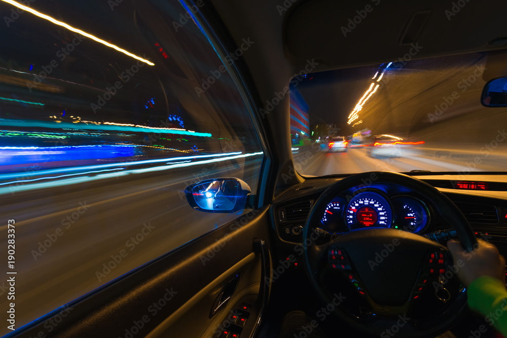 Movement of the car at night on the country highway at a high speed of viewing from the inside with the driver. Hand on the wheel of the car. Forward movement