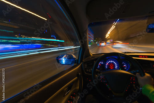 Movement of the car at night on the country highway at a high speed of viewing from the inside with the driver. Hand on the wheel of the car. Forward movement