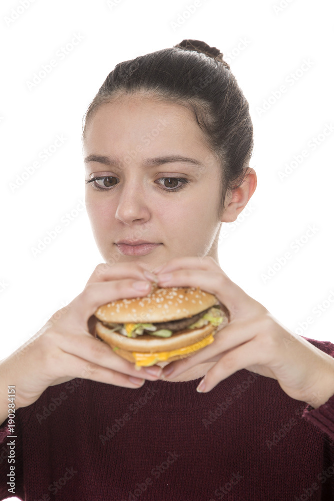 Adolescent girl looking suspiciously at a hamburger on a white background