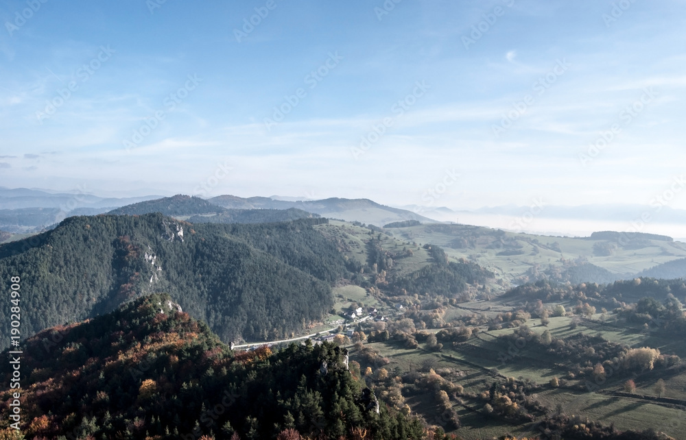 autumn mountain countryside with hills, meadows, colorful forest, blue sky with mist in valleys in Slovakia