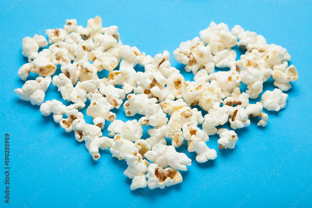 Popcorn in the shape of heart on a blue background. Popcorn in the shape of heart on a blue background.