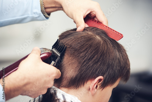 European boy getting haircut in barbershop.