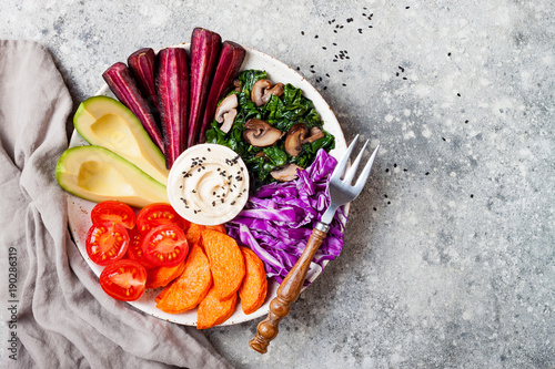 Buddha bowl with roasted butternut, hummus, shredded red cabbage, tomatoes, avocado, purple carrots, sauteed spinach, mushrooms. Healthy vegetarian appetizer or snack platter. Veggies detox lunch bowl