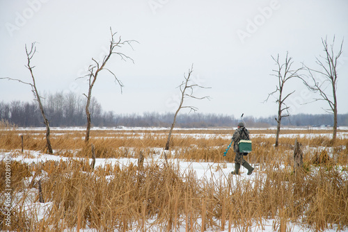 Fisherman is walking on lake at winter, ice fishing