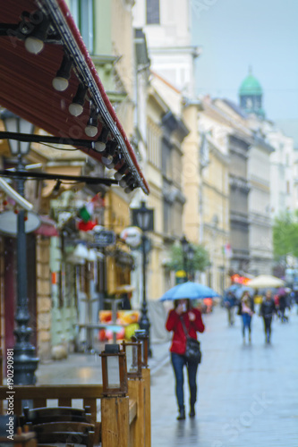 European city street, rain, blurred person with umbrella and handkerchief