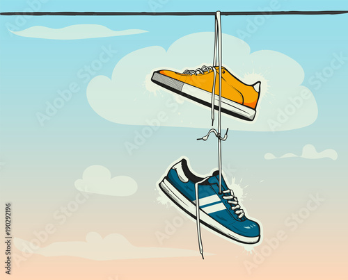 Sneakers hanging from a rope on the background of clouds