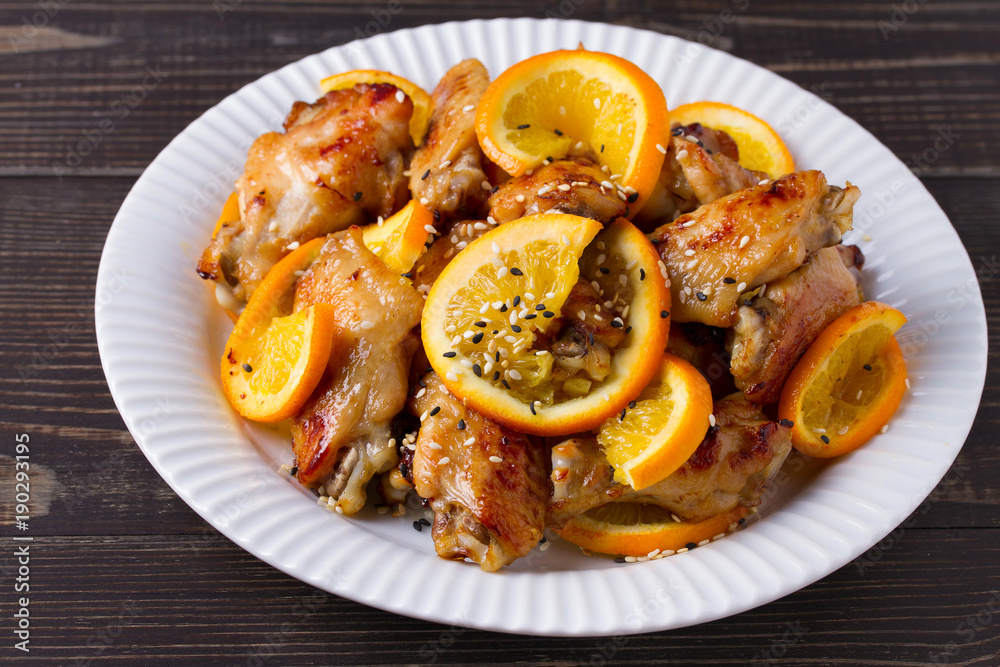 Sweet and sour chicken wings with oranges, served with sesame on white plate Sweet and sour chicken wings with oranges, served with sesame on white plate