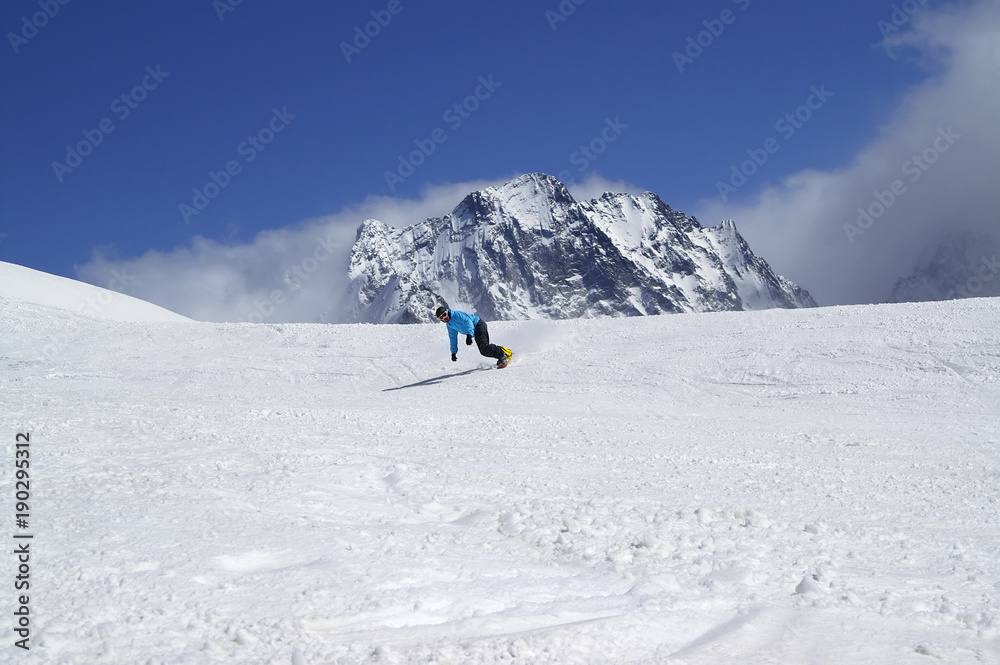 Snowboarder downhill in high snowy mountain