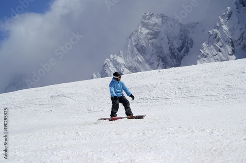 Snowboarder downhill on snowy ski slope in high mountain