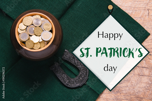 Beautiful green and wooden background for Saint Patrick's day celebration. Leprechaun pot of gold. Great party at the 17th March. Patric's postcard design. Horseshoe as a symbol of the holiday.
