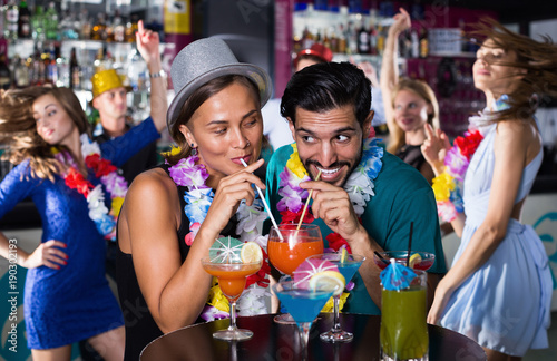 Man with female drinking cocktails on hawaiian party