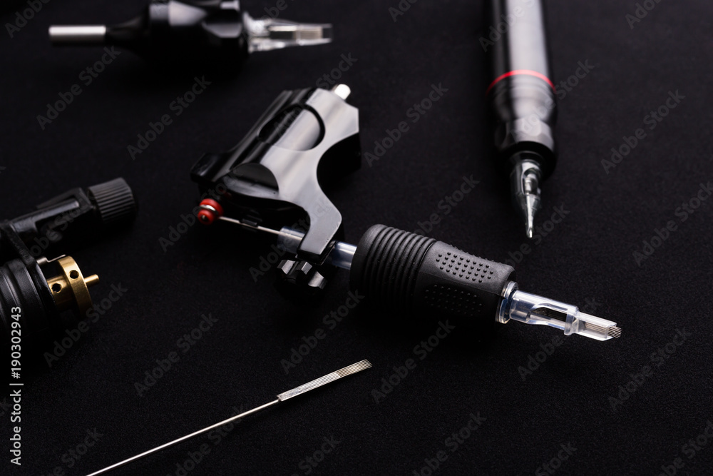 Tattoo machine and tattoo supplies on dark background Tattoo machine and tattoo supplies on dark background
