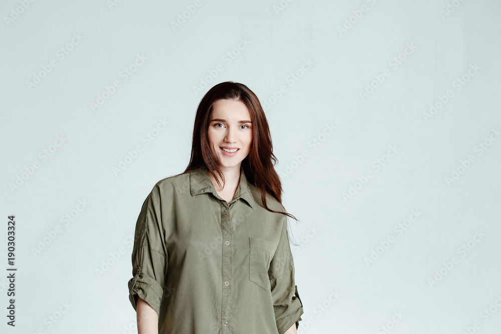 Portrait of a pretty smiling woman brunette with long hair in a green shirt dress posing isolated on a white background Portrait of a pretty smiling woman brunette with long hair in a green shirt dress posing isolated on a white background