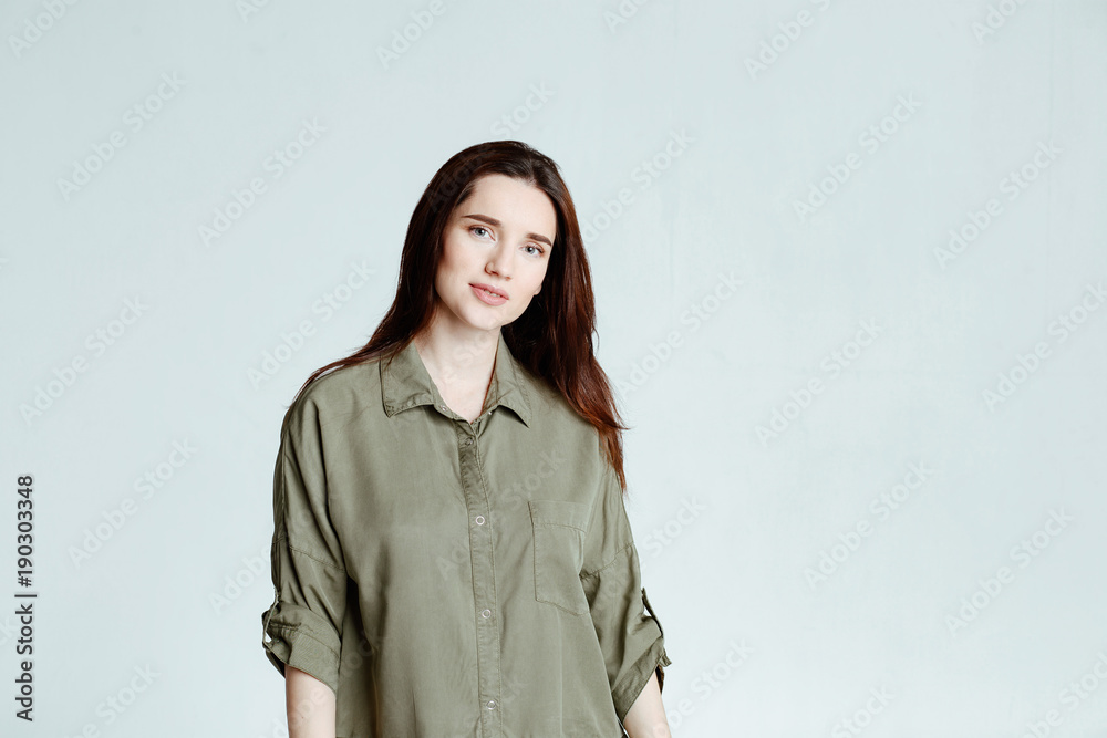 Portrait of a pretty smiling woman brunette with long hair in a green shirt dress posing isolated on a white background Portrait of a pretty smiling woman brunette with long hair in a green shirt dress posing isolated on a white background