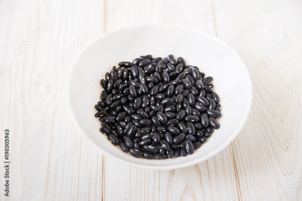 black kidney beans in the white plate.wooden background. black kidney beans in the white plate.wooden background.