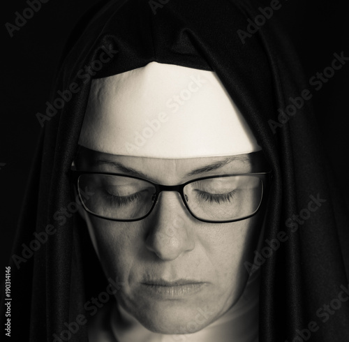 nun praying with eyes closed in black and white