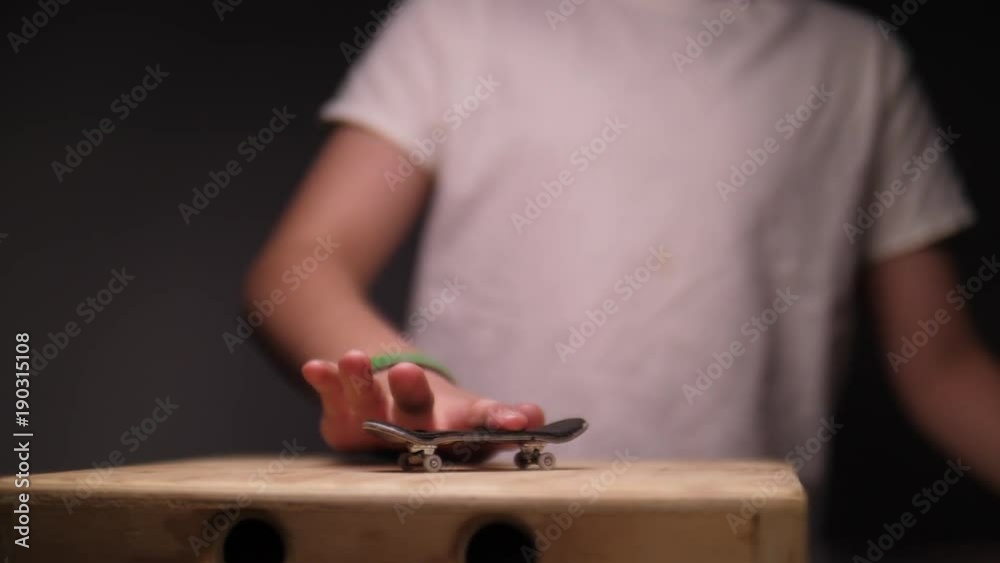 KID DOING FINGER SKATEBOARD TRICK, IN SLOW MOTION